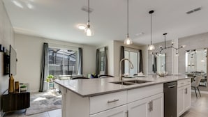 A modern kitchen with a central island, pendant lighting, and a large window. - Rent a Luxury Townhome on Storey Lake Resort, Minutes From Disney, Orlando Townhome 3224 (Kissimmee)