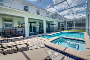 A pool area with lounge chairs and a hot tub, enclosed by a glass structure.