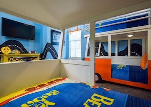Ein Kinderzimmer mit Bett, Spielbereich und Fernseher.