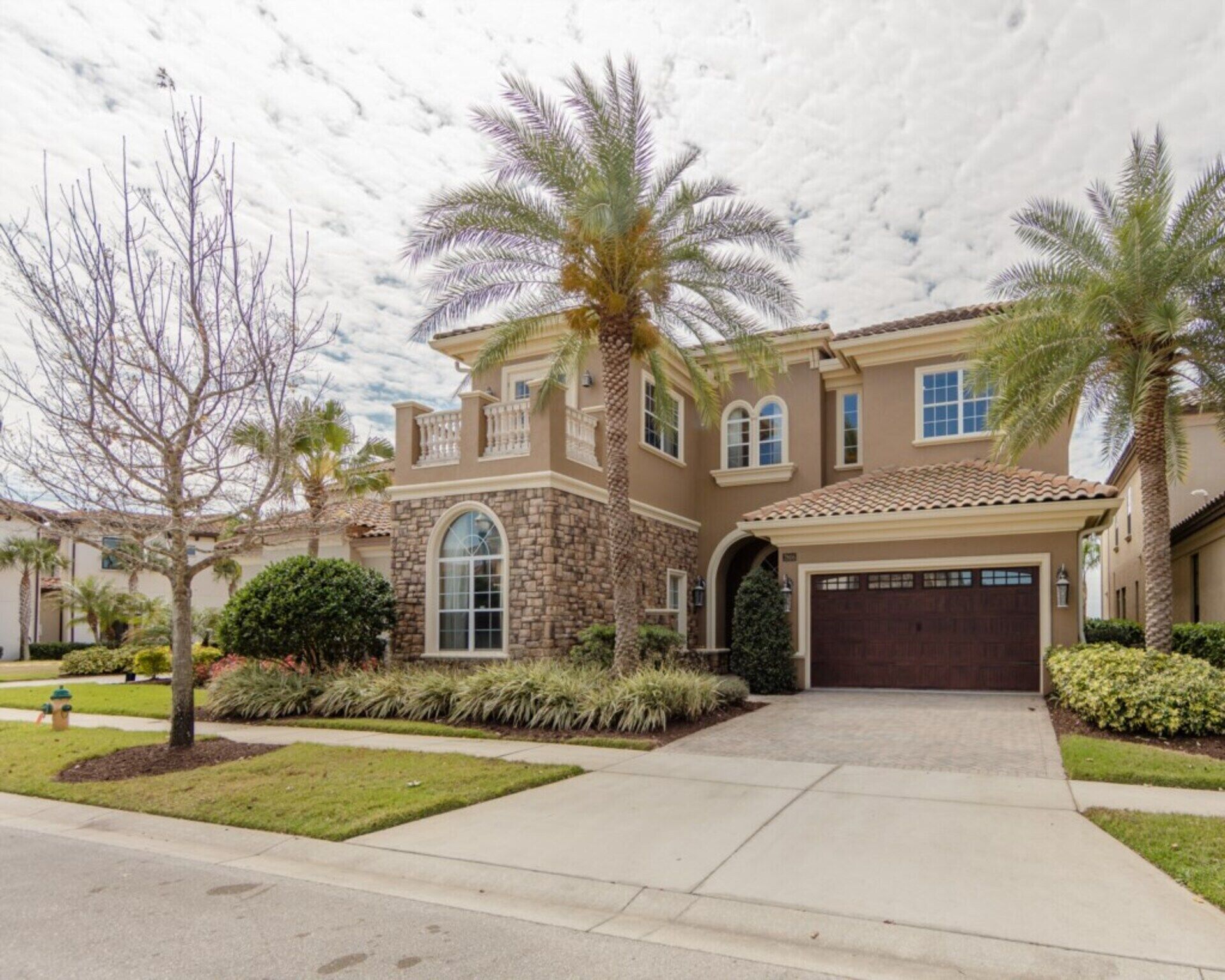A two-story house with a stone facade, a large arched window, and a garage.