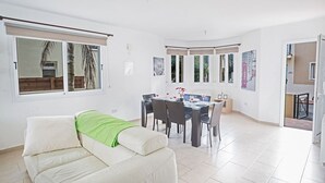 A spacious living room with a dining area, large windows, and a view of the outdoors. - Cyprus Villa Near the Beach, Paralimni Villa 1198 (Paralimni)