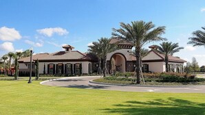 A large, multi-story building with a curved driveway and palm trees.