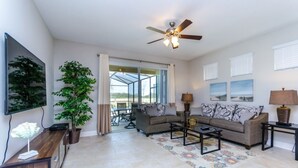 A spacious living room with a ceiling fan, a large window, and a view of the outdoors.