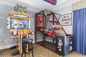 Ett rum med en lekplats som innehåller en spelmaskin med Transformers-tema, en klätterställning och en basketkorg.