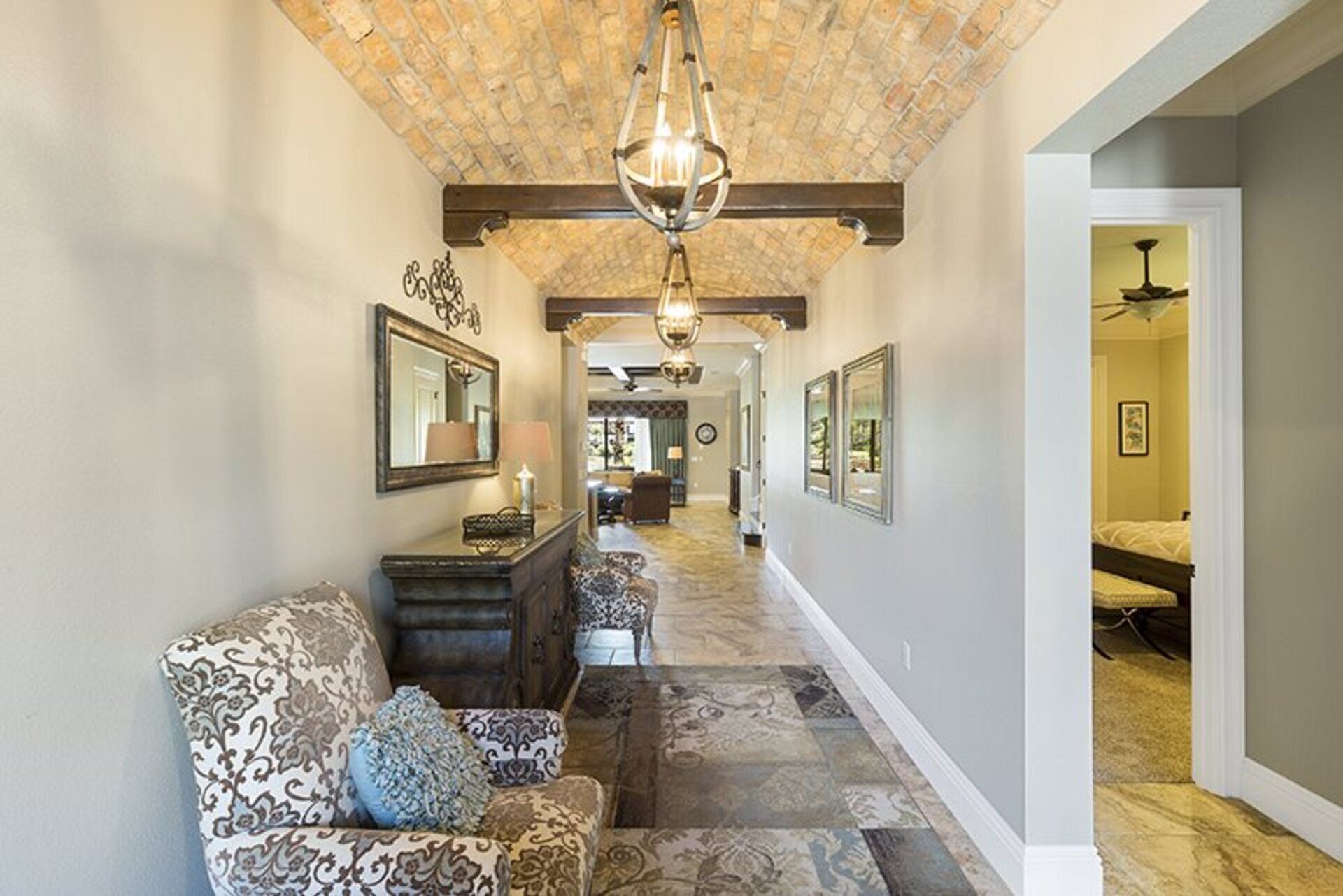 A hallway with patterned carpet, a sofa with cushions, a mirror, and a chandelier.