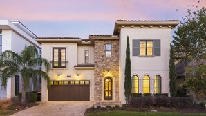 Une maison à deux étages avec un garage, une façade en pierre et une pelouse bien entretenue.
