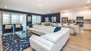 A modern living room with a white sofa, a glass coffee table, and a blue patterned rug. - Beautiful Mansion With Private Pool, Close to Disney, Orlando Mansion 2659 (Kissimmee)