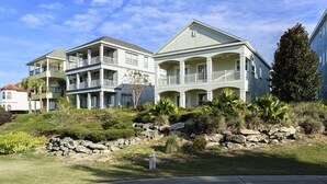 A two-story beachfront property with multiple balconies and a stone retaining wall.