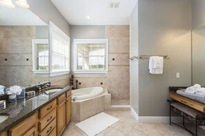 A modern bathroom with a bathtub, a vanity with a mirror, and a window. - Luxury 6 Bedroom Villa on Reunion Resort, Orlando Villa 3479 (Kissimmee)