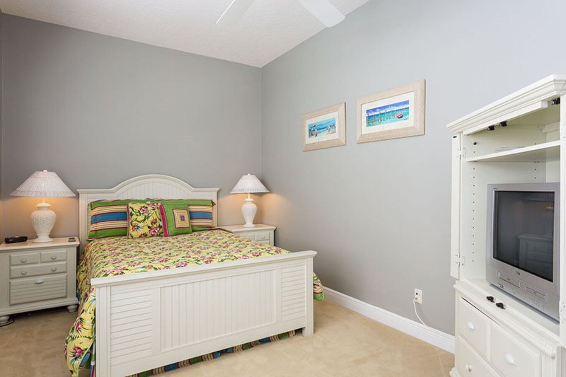 Une chambre à coucher comprenant un lit, des tables de chevet, une commode et un téléviseur.