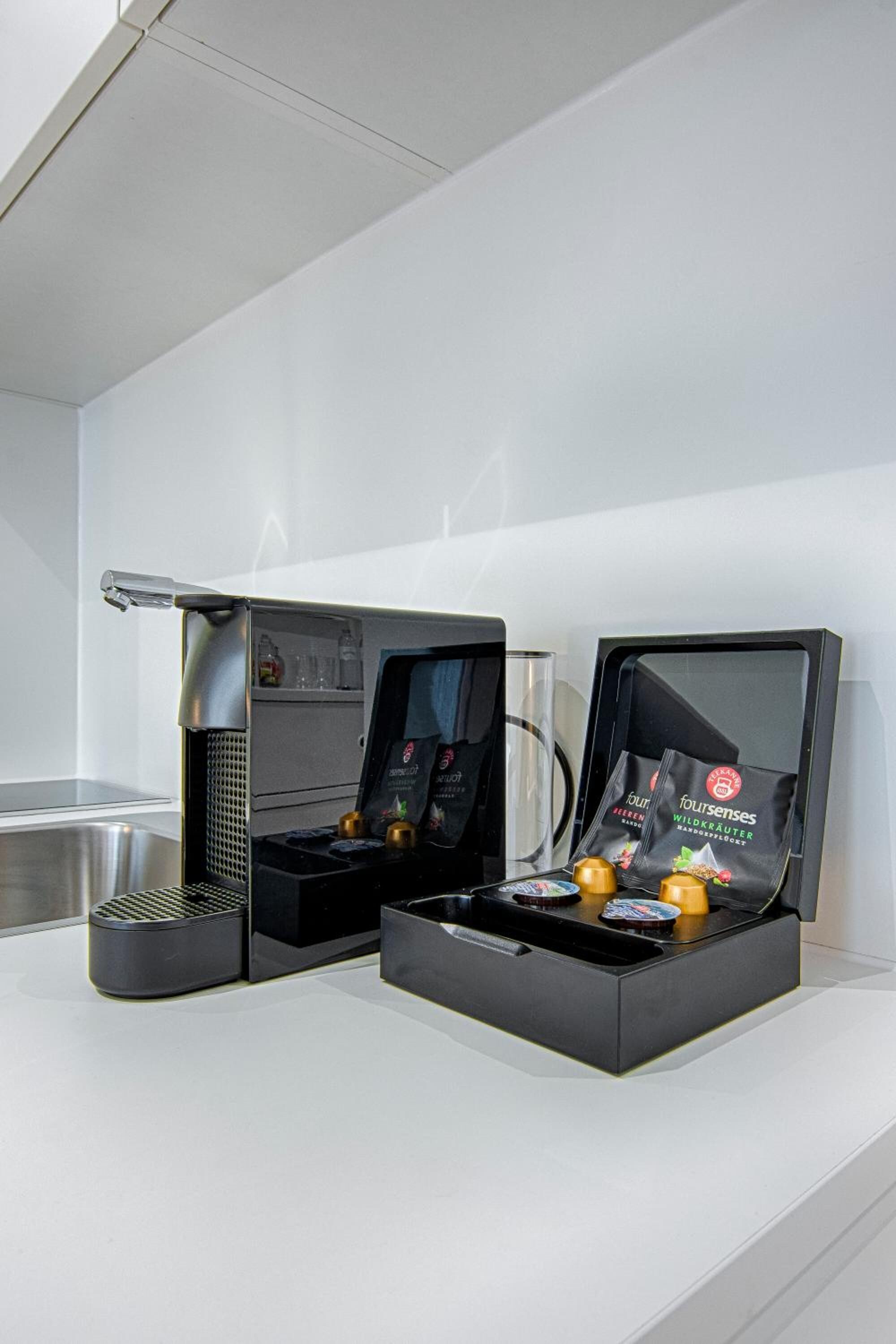 Eine moderne Kaffeemaschine mit digitalem Display, einer Kaffeemühle und einer Schachtel mit Kaffeekapseln.