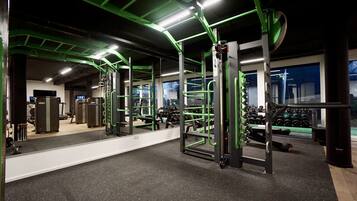 A gym with green equipment, a large mirror, and weight racks.