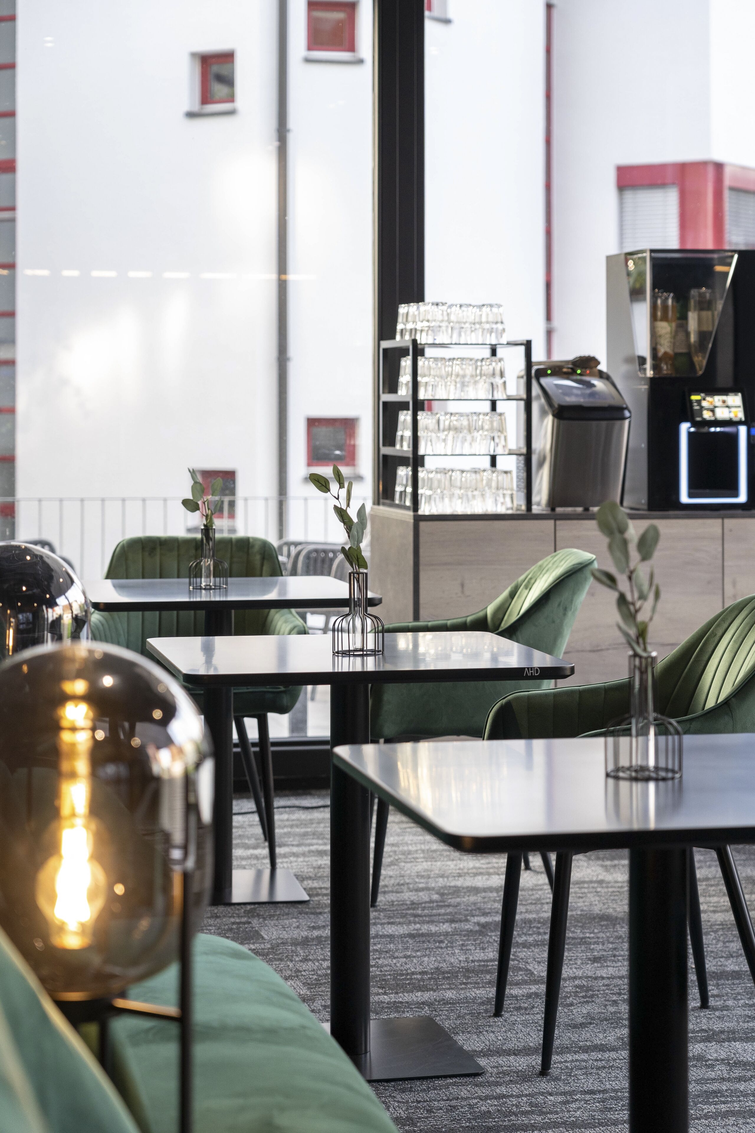 An outdoor seating area with tables and chairs, a trash bin, and a vending machine.