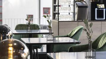 An outdoor seating area with tables and chairs, a trash bin, and a vending machine.