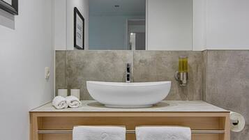 A modern bathroom with a large white sink, two towels, a toilet, and a mirror above the sink.