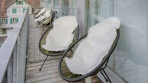 A balcony with two white cushioned chairs and a wooden deck.