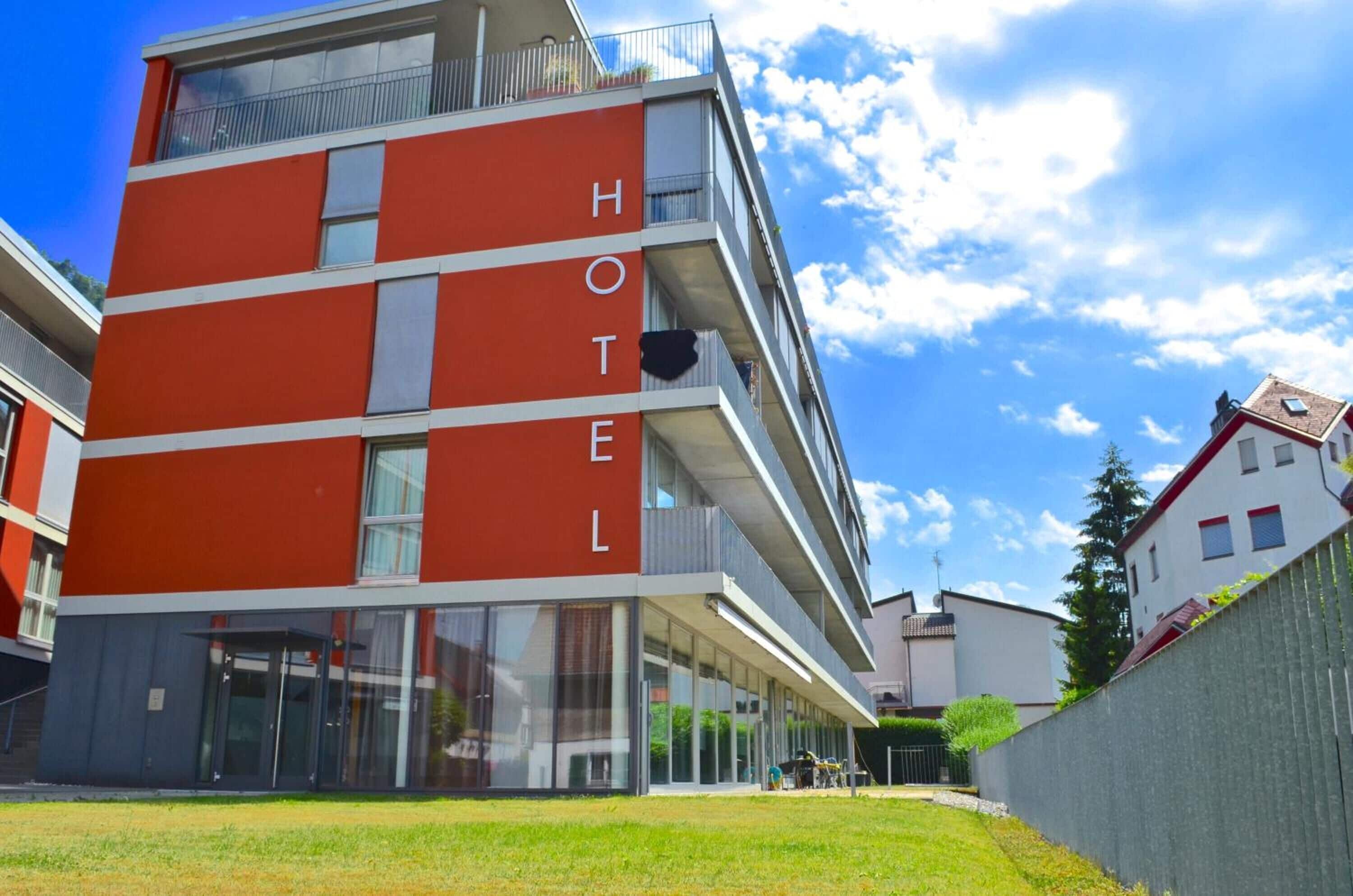 Un hotel de varios pisos con fachada roja y balcones.