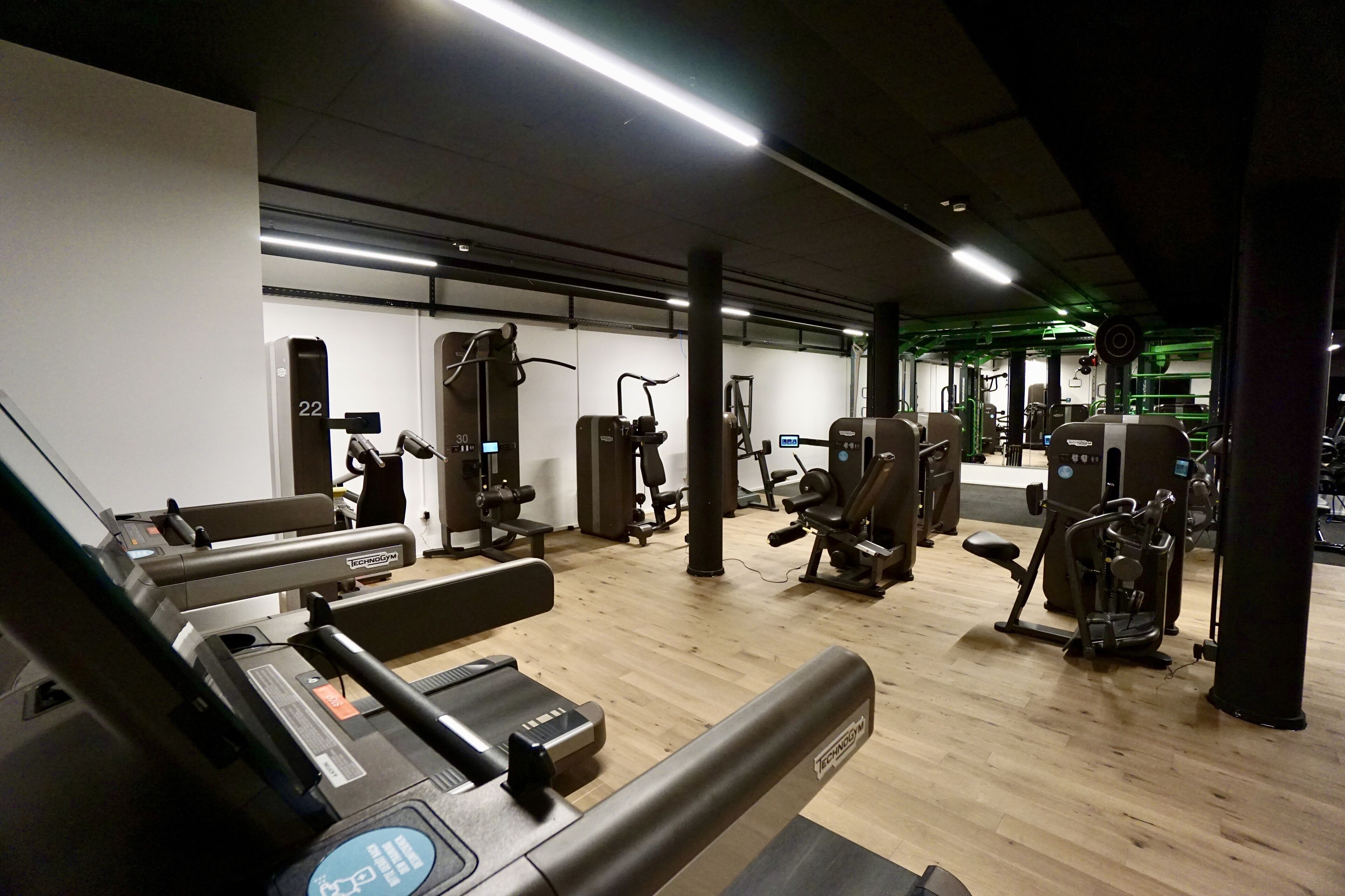 Un gimnasio con varias máquinas de ejercicio, una cinta de correr y un banco para pesas.
