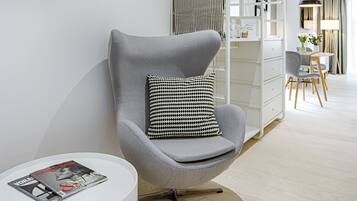 A modern living room with a grey armchair, a round white side table, and a bookshelf.
