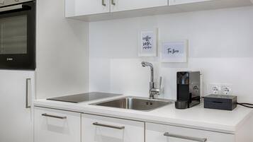 A modern kitchen with white cabinetry, a Bosch oven, a sink with a faucet, and two framed signs on the wall.