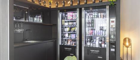 Une cuisine moderne équipée d’un évier, de deux distributeurs automatiques de boissons et d’une plante en pot.