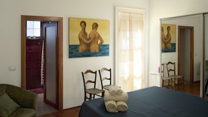 Une chambre d’hôtel avec un lit, deux chaises, un tableau et un miroir.