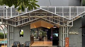 A modern hotel entrance with a covered outdoor seating area, a reception desk, and a visible pool. - BOOK Design Hotel (Chiang Mai)