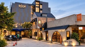 A hotel with a modern design, featuring a prominent 'BOOK HOTEL' sign, a 'BOOK THIEF' cafe, and a 'CUSTOMER PARKING ONLY' sign. - BOOK Design Hotel (Chiang Mai)