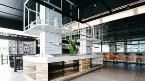 A modern kitchen with a central island, bar stools, and a large window providing natural light. - BOOK Design Hotel (Chiang Mai)