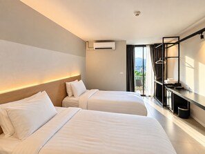 A hotel room with two beds, a desk, a wardrobe, and a view of the outdoors. - BOOK Design Hotel (Chiang Mai)