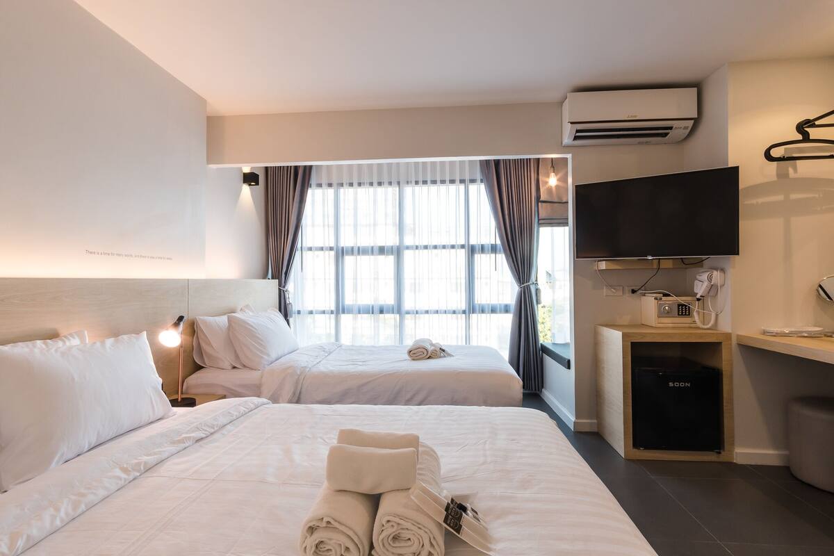 Ein Hotelzimmer mit zwei Betten, einem Fernseher, einer Klimaanlage, einem Telefon und einem kleinen Schrank.