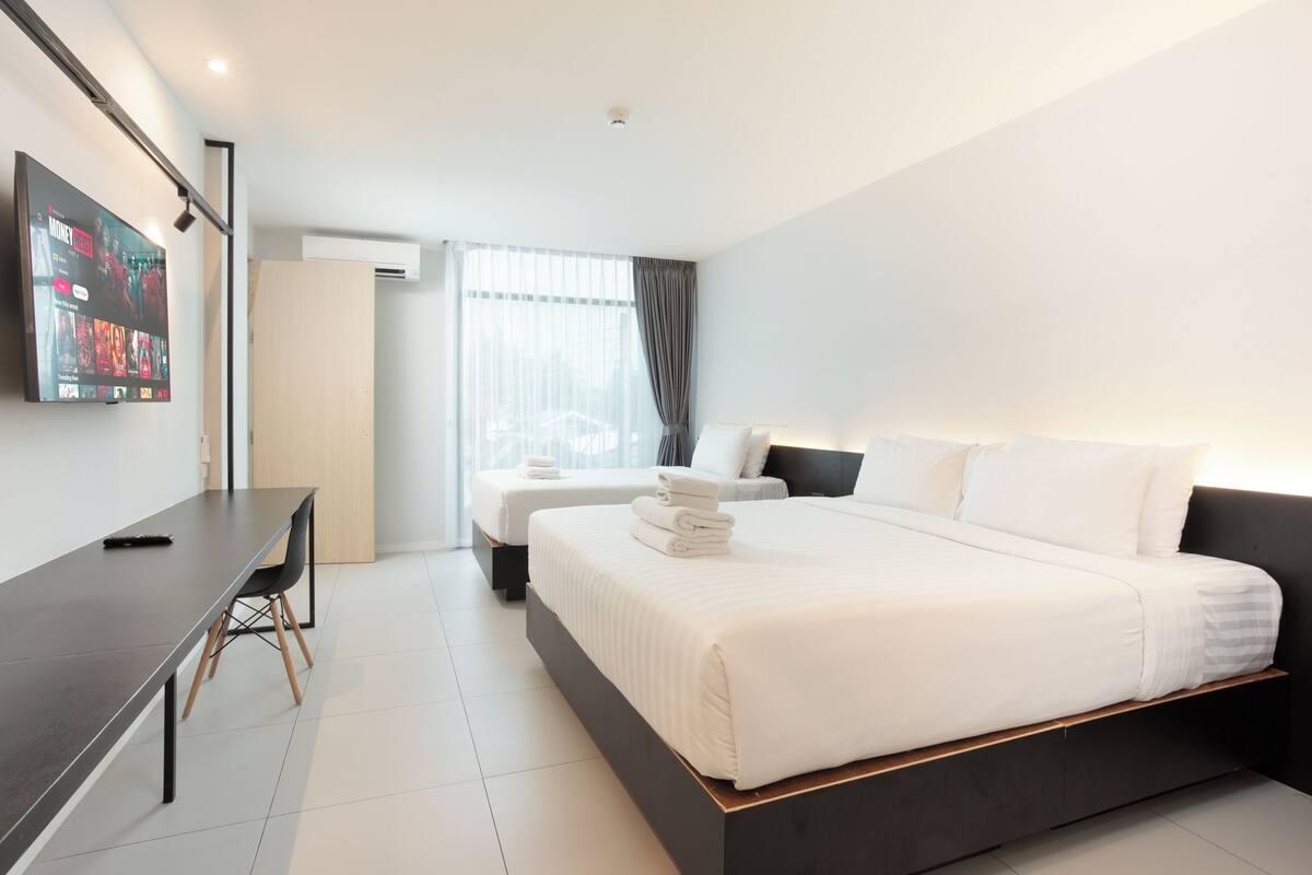 Ein modernes Hotelzimmer mit einem großen Bett, einem Schreibtisch und einem an der Wand befestigten Flachbildfernseher.