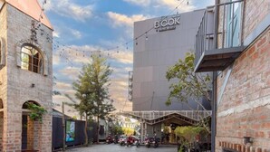 A courtyard with a modern building labeled "BCOR HOTEL BYSTY" and a smaller brick structure with a tower. - BOOK Design Hotel (Chiang Mai)