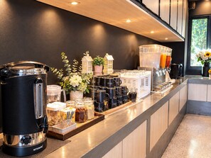 A coffee station with a coffee maker, mugs, and a juice dispenser. - BOOK Design Hotel (Chiang Mai)