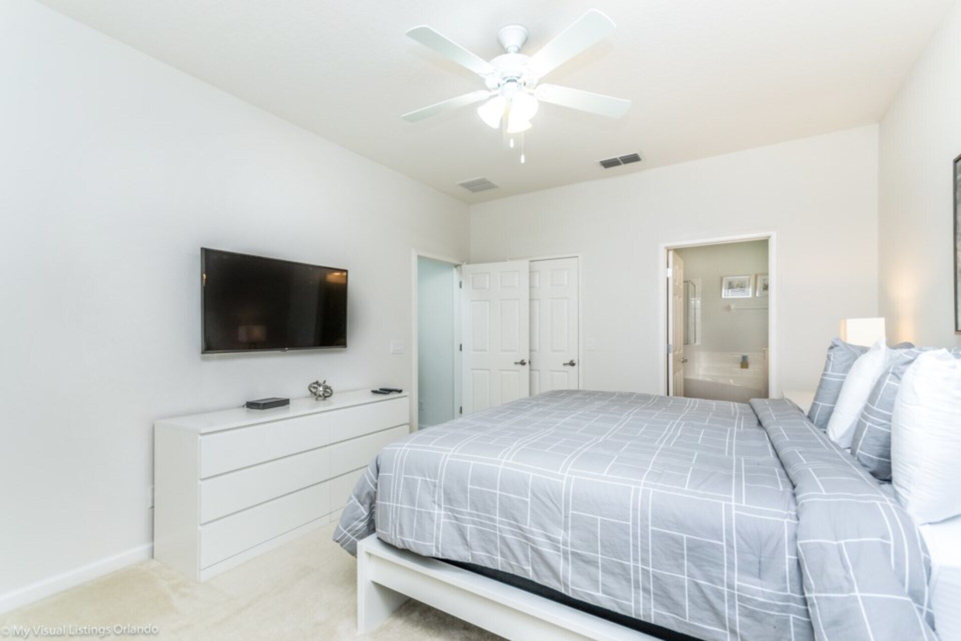 A bedroom with a bed, a TV, a dresser, and a closet.