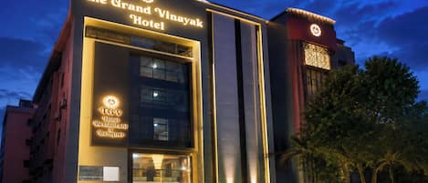 A hotel with a prominent sign reading 'The Grand Vinayak Hotel' and a smaller sign for 'TGV Hotel Restaurant & Banquet.'
