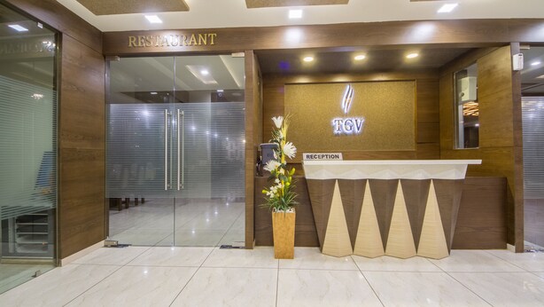 A reception area with a wooden reception desk, a glass door entrance, and a sign that reads "RECEPTION". - The Grand Vinayak Hotel (Ahmedabad)