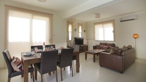 A spacious living area with a dining table set for four, a sofa, and a television. - Beautiful Villa With Private Pool, Protaras Villa 1020 (Paralimni)