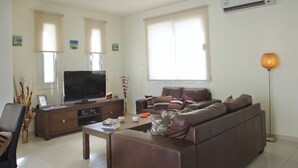 A living room with a brown sofa, a television, a coffee table, and a floor lamp. - Beautiful Villa With Private Pool, Protaras Villa 1020 (Paralimni)