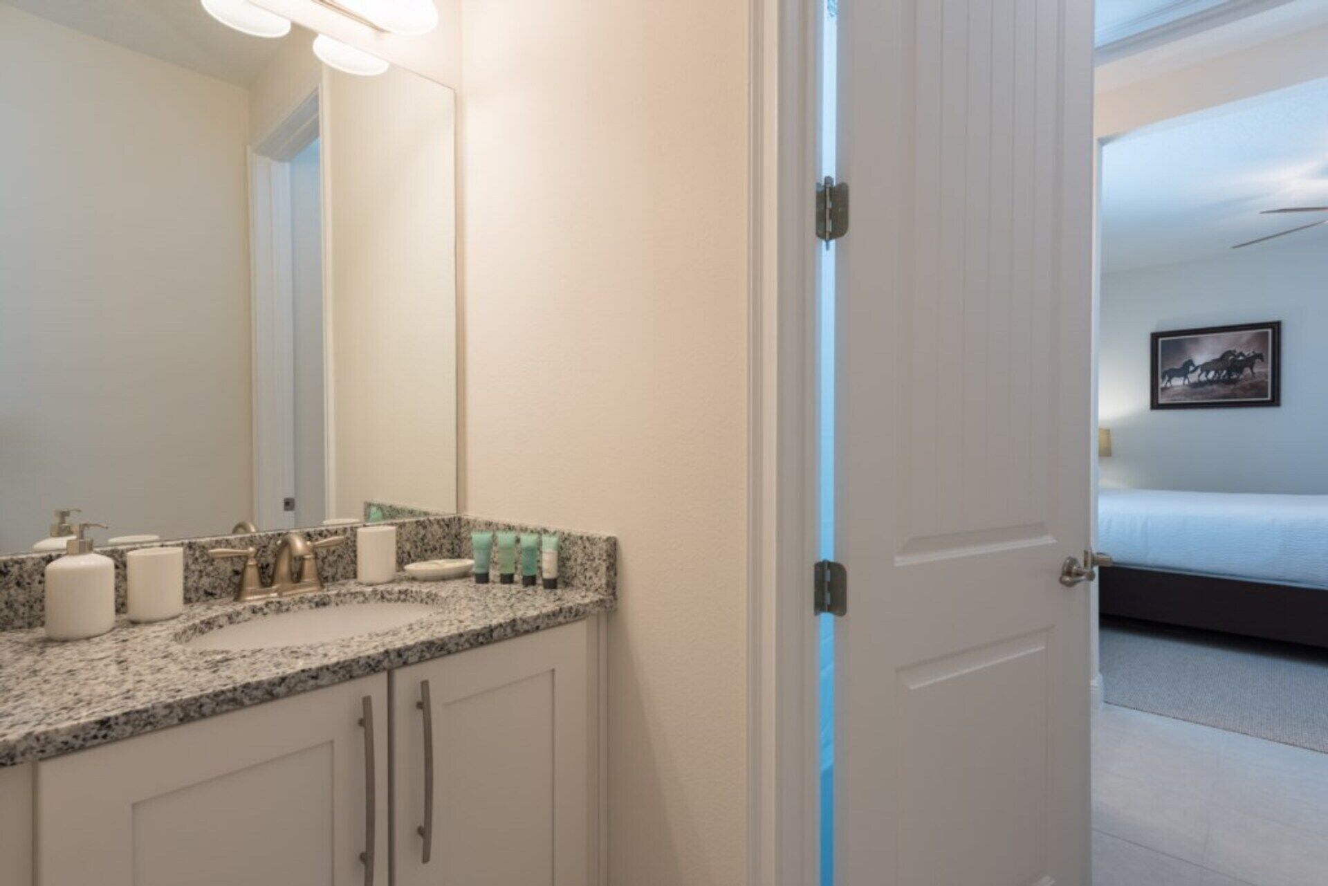 A hotel bathroom with a granite countertop, a large mirror, and toiletries.