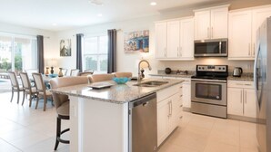 A modern kitchen with white cabinets, stainless steel appliances, and a central island.