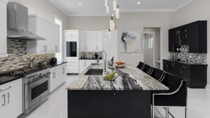 A modern kitchen with a central island, stainless steel appliances, and a black and white marble countertop. - Beautiful Villa With Private Pool, Close to Disney, Orlando Villa 2949 (Kissimmee)