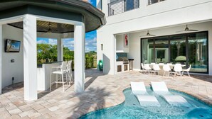 A modern outdoor pool area with a hot tub, lounge chairs, and a barbecue setup. - Beautiful Villa With Private Pool, Close to Disney, Orlando Villa 2949 (Kissimmee)