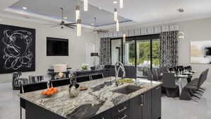 A modern kitchen with a large island, dark cabinetry, and pendant lighting. - Beautiful Villa With Private Pool, Close to Disney, Orlando Villa 2949 (Kissimmee)