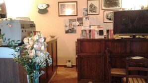 A living room with a wooden cabinet, a television, a clock, and various framed pictures on the wall. - Room in B&B - A Little Place in Tuscany Where to Relax (Montaione)