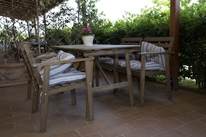 A wooden outdoor seating area with a table and chairs, surrounded by greenery. - Room in B&B - A Little Place in Tuscany Where to Relax (Montaione)