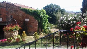 A rustic stone building with a brick roof, surrounded by potted plants and flowering shrubs. - Room in B&B - A Little Place in Tuscany Where to Relax (Montaione)