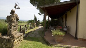 A stone structure with a trident, a covered patio with outdoor seating, and a view of the countryside. - Room in B&B - A Little Place in Tuscany Where to Relax (Montaione)