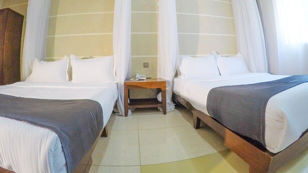 A hotel room with two beds, a nightstand, and a telephone. - Metropak Hotel Breweries (Kisumu)