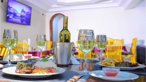 A dining table set with plates of food, glasses of wine, and a bottle in a bucket. - Metropak Hotel Breweries (Kisumu)